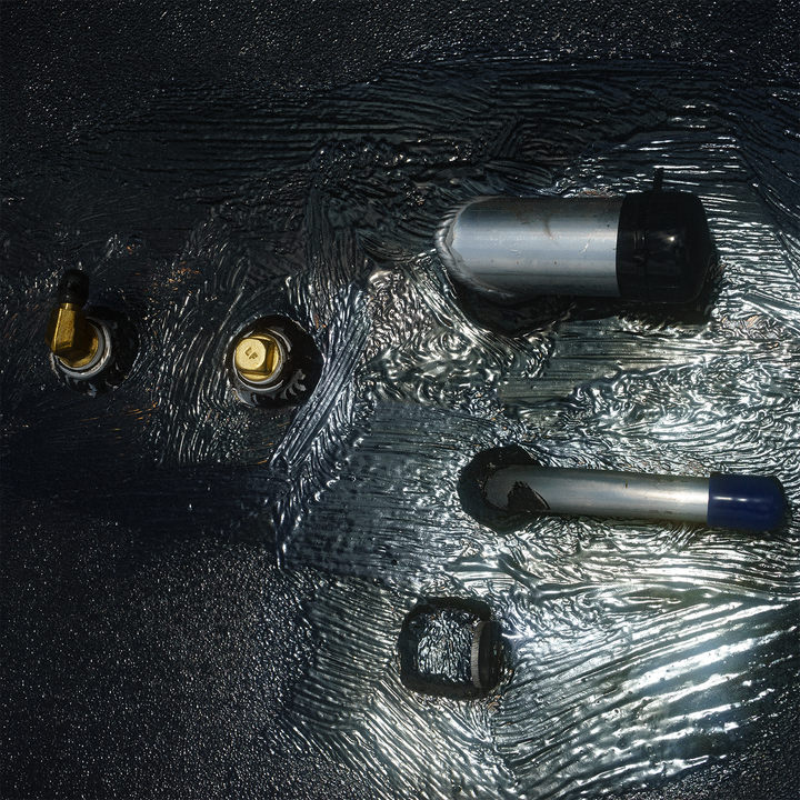 Close-up view of a Mako 23.5 OEM replacement belly fuel tank with a 160-gallon capacity, featuring various fittings and connectors on a textured surface