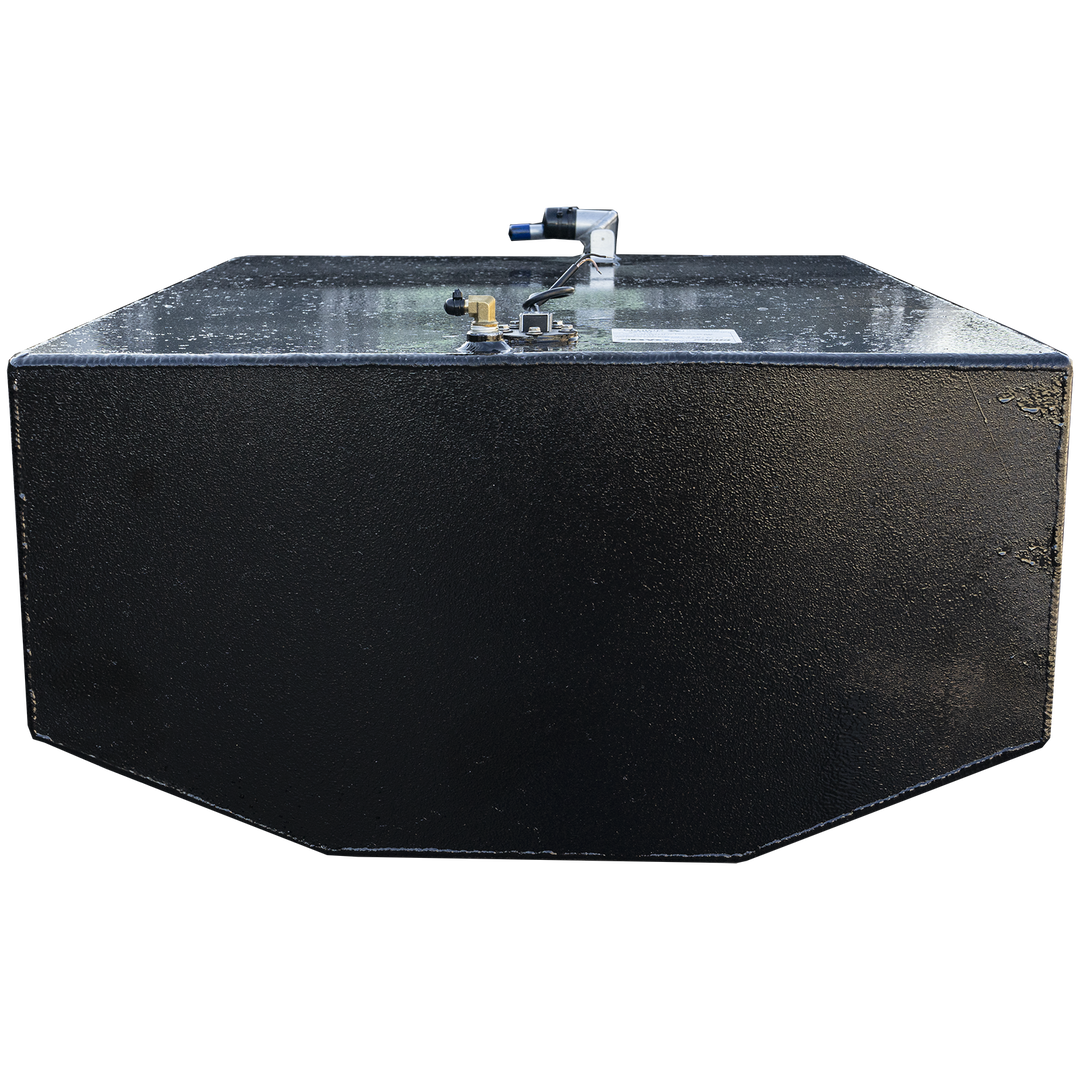A black, rectangular fuel tank with a textured surface and chamfered bottom edges is positioned against a black and grey checkerboard background. Its top surface features various fittings, including a brass-colored valve, a white label, and a white and blue hose connection. The lighting highlights the texture of the tank and the metallic sheen of the fittings