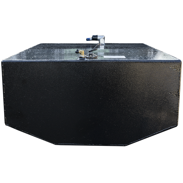 A black, rectangular fuel tank with a textured surface and chamfered bottom edges is positioned against a black and grey checkerboard background. Its top surface features various fittings, including a brass-colored valve, a white label, and a white and blue hose connection. The lighting highlights the texture of the tank and the metallic sheen of the fittings