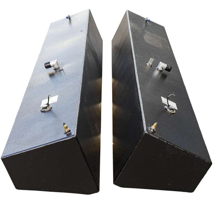 A matching pair of tall, narrow, black-coated saddle fuel tanks, presented as a port and starboard combo. The tanks are standing upright side-by-side against a checkered background, angled slightly to show they are a mirror-image set. Each tank features an identical arrangement of fittings on its top surface, including a fuel sending unit, several valve fittings, and a white manufacturer's label