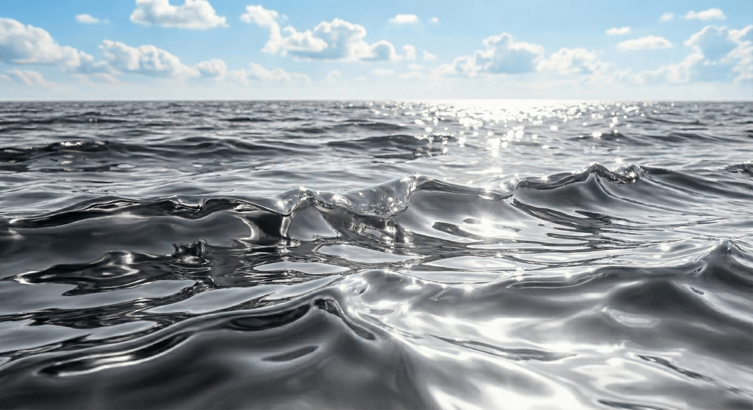 A close-up image of smooth, shiny silver fabric with soft folds and flowing curves.