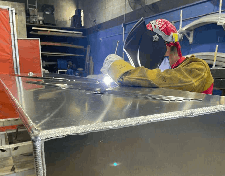 Certified welder performing precision TIG welding on a custom aluminum marine fuel tank at Welding World Inc. in Miami.