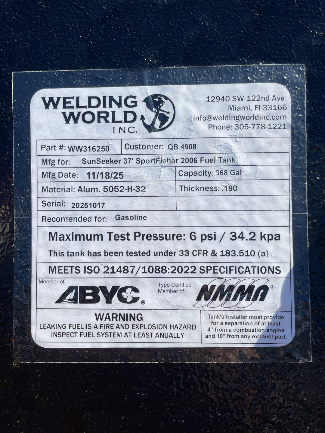 A close-up photo of the white specification label on a dark textured boat fuel tank. The Welding World Inc. label lists the part as WW316250, manufactured for a "SunSeeker 37' SportFisher 2006 Fuel Tank," with a 368-gallon capacity.