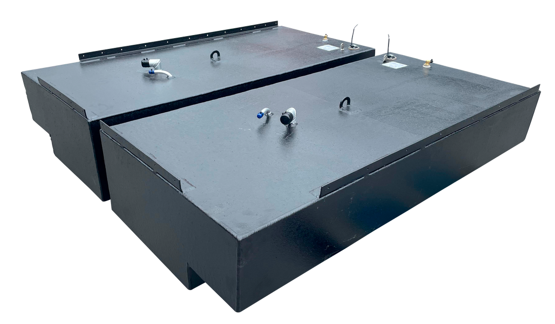 Angled top-down view showing the rectangular shape and surface detail of two adjacent black marine fuel tanks, with various hose fittings and lifting eyes visible on the lids.