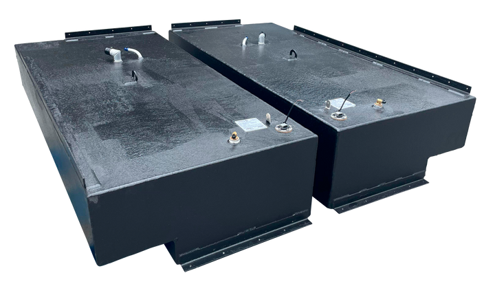 Angled view of two black rectangular marine fuel tanks (Stama 2001) showing various brass and plastic fittings, electrical connections, and lifting eyes on the forward end of the tank tops.