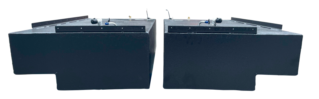 Straight side-on profile of the two black rectangular Stama 2001 marine fuel tanks, highlighting their long length, dark texture, and metal mounting rails along the upper edge.