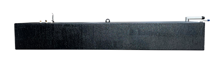 A side elevation photograph of an elongated black marine fuel tank showing its uniform rectangular height and textured surface. The top surface is visible, displaying two brass fittings at the left end, a central lifting eye, and a silver fill neck assembly at the far right end.