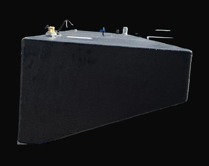 A side-angle photograph of the center fuel tank focusing on its textured black finish and its angled side wall. The image captures the top-mounted hardware, including a brass fitting and electrical lead, while demonstrating the tapering depth of the tank's hull-fitting design.