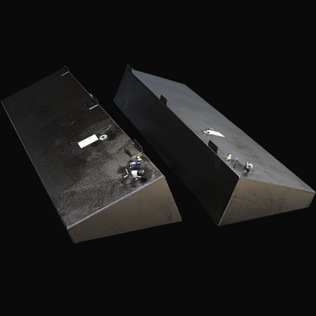 Two black marine fuel tanks side by side with angled ends and multiple fittings on top. Each tank has a white label and mounting brackets. Described as Advanced 33 model with 128 gallons net capacity each, an OEM replacement saddle fuel tank combo