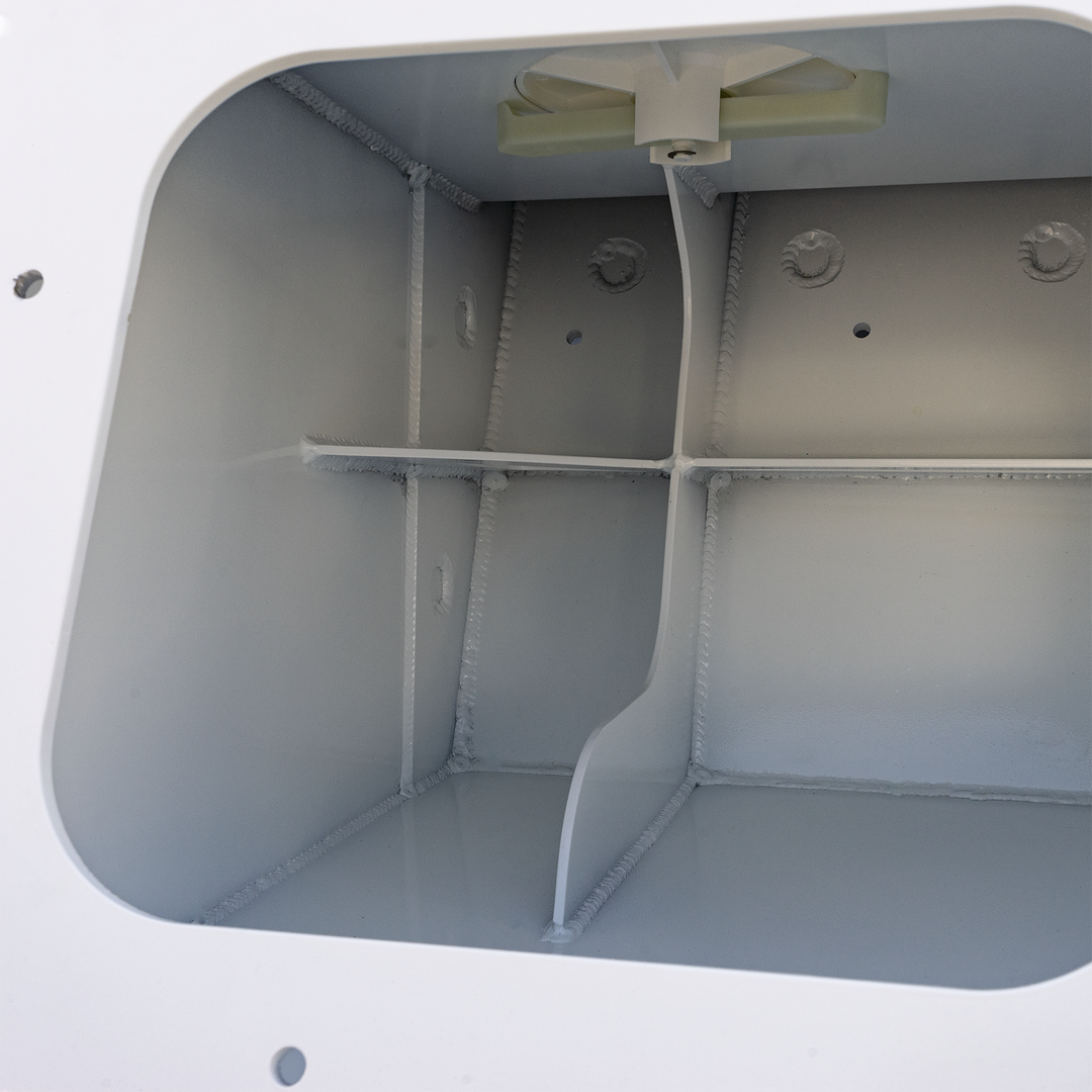 The interior of a white metal enclosure showing the Apex Triple NSP 3-Engine Bracket, which is a beige-colored, T-shaped component mounted at the top center inside the box, with a cable or wire hanging from it. The inside walls have visible welds and small hole