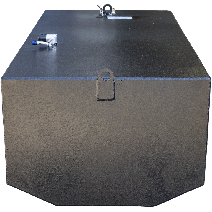 Black rectangular marine fuel tank with flat top and angled front bottom corners. The tank has a welded lifting eye in the center front, fittings including white and black pipes with blue caps on the top left, and a label mounted near the center back. The surface shows texture and welding marks. The background is transparent