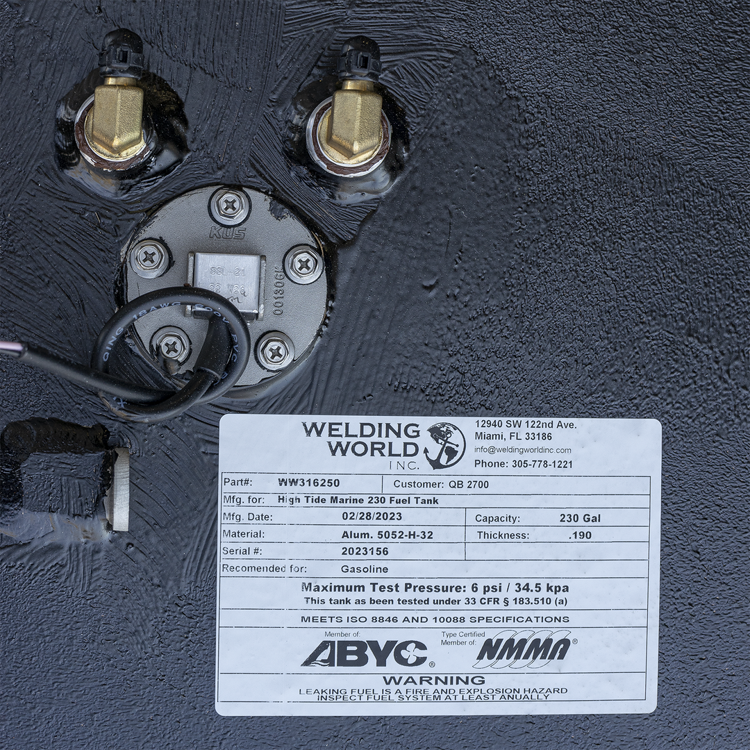 Black marine fuel tank surface with brass fittings and electrical wiring near a round metal plate. Below is a white label showing Welding World logo, part number WW316250, customer QB 2700, made for High Tide Marine 230 fuel tank, dated 02/28/2023, capacity 230 gallons, aluminum material, .190 thickness, serial number 2023156, certified by ABYC and NMMA, with safety warning about fuel leaks