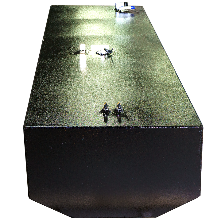 A close-up, elevated view of a black metal box with a subtly textured, glittery top surface. Several small, metallic fixtures are attached to the surface, and a single pipe extends from the top right. Reflections of light are visible on the surface. The background is a checkered pattern of black and transparent squares
