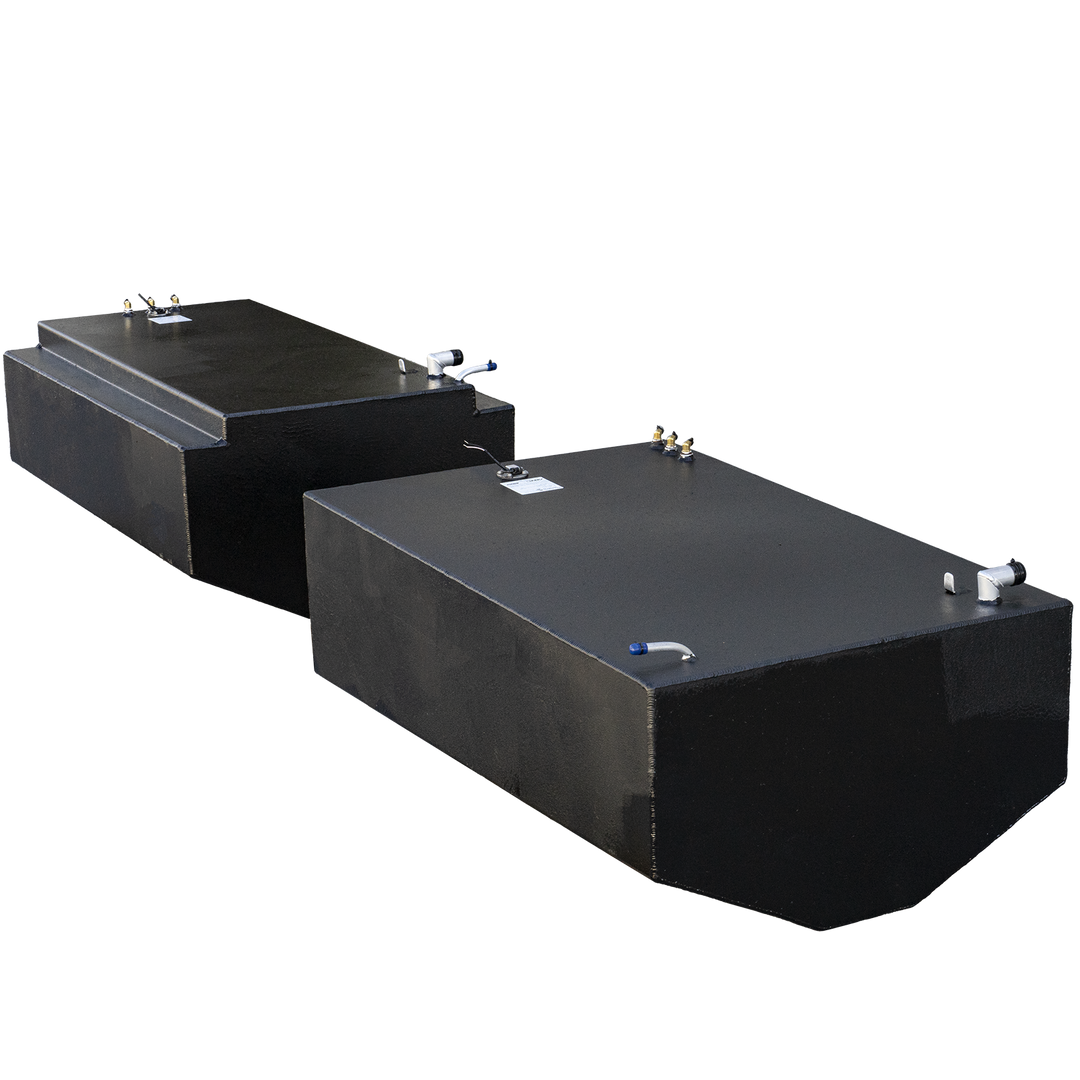 Two black Carrera 36 OEM Replacement Saddle 2-Fuel Tanks, one with a stepped top and the other a simple rectangular shape, are arranged side-by-side. Both tanks have various fittings and connectors on their top surfaces, including white and blue pipe assemblies and brass-colored elements. The tanks appear to be made of a textured, matte material
