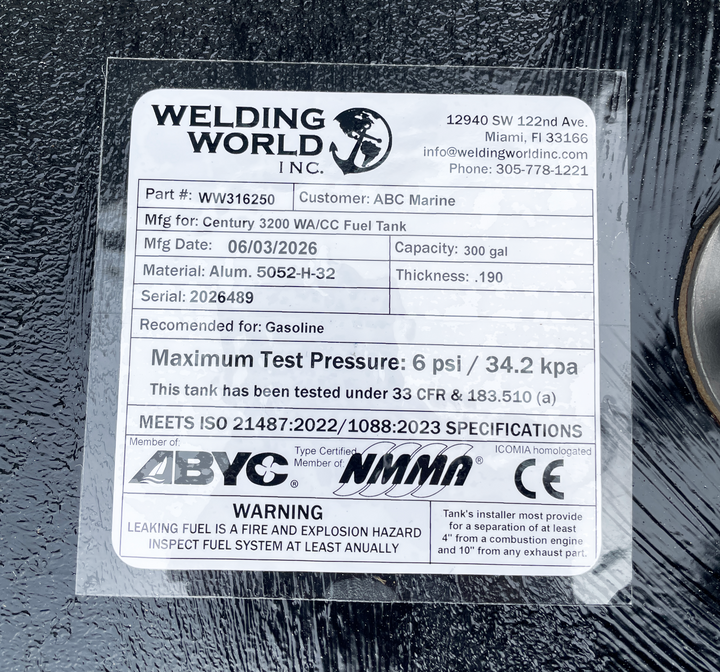 Close-up top-deck hardware layout view of a black Century 3200 WA/CC replacement marine fuel tank. The image focuses on a clear manufacturer specification data placard listing part number WW316250, customer name ABC Marine, and a manufacturing date of 06/03/2026. Fabricated from heavy-gauge marine-grade 5052-H32 aluminum with a thickness of .190, the 300-gallon capacity center-hull tank body is fully encapsulated in a textured, anti-corrosive black TarGard epoxy coating. Every unit is precision-engineered b