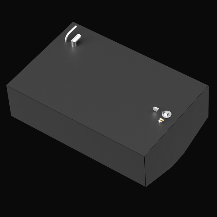 A 3D model rendering of a black rectangular fuel tank with a flat top. The tank has two protruding pipes on the left side and multiple fittings including a capped inlet and a mounting bracket on the right side. The front bottom edge of the tank is angled inward, giving it a tapered shape