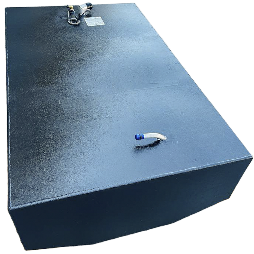 A dark, rectangular fuel tank with a textured surface is positioned at an angle against a black and grey checkered background. On its top surface, there are various fittings including a small curved pipe with a blue tip on one end, and a cluster of several nozzles and a white label on the other