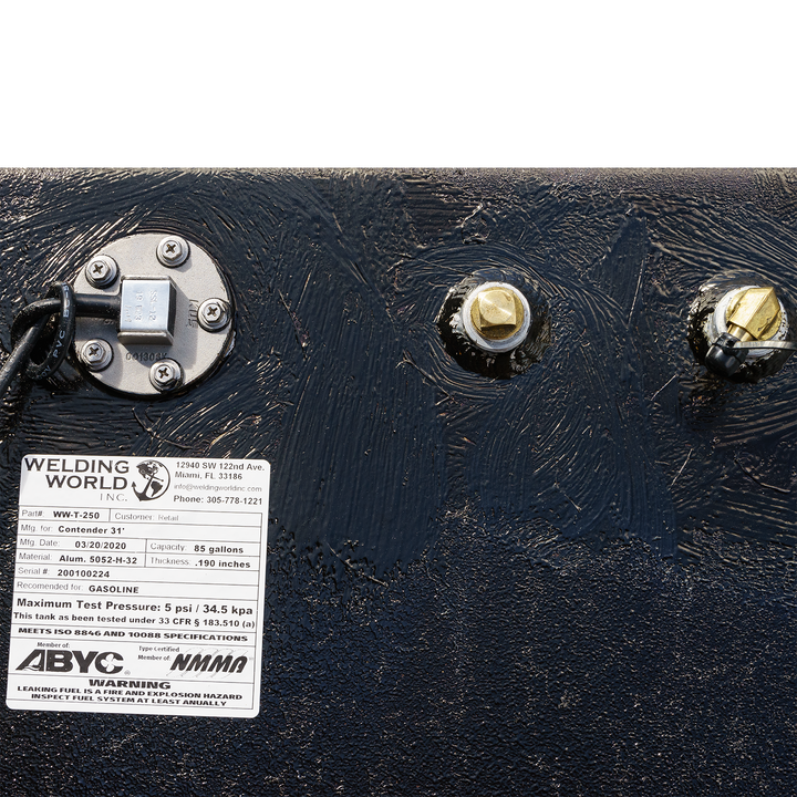 Close-up of a fuel tank assembly featuring a large belly tank with a capacity of 128 gallons, two standard saddle tanks each holding 85 gallons, and a water tank with a capacity of 21.26 gallons. The image shows the tank's fittings, including a fuel gauge and connection points, along with a label indicating specifications and safety information