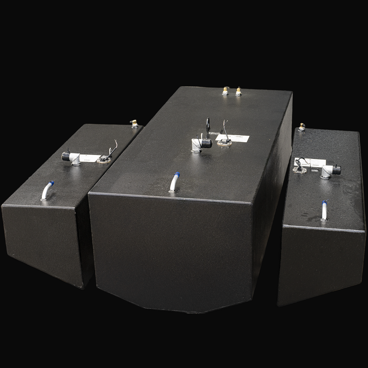 Three black metal fuel tanks arranged side by side on a transparent background. The central tank is larger with a beveled front edge, while two smaller tanks flank it on either side. Each tank has fittings, capped openings, and wires on top