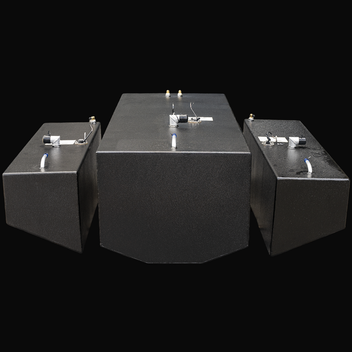 Front view of three black metal fuel tanks positioned side by side on a transparent background. The central tank is larger with a beveled front edge, flanked by two smaller rectangular tanks on each side. Each tank has metal fittings, capped openings, and wiring on top