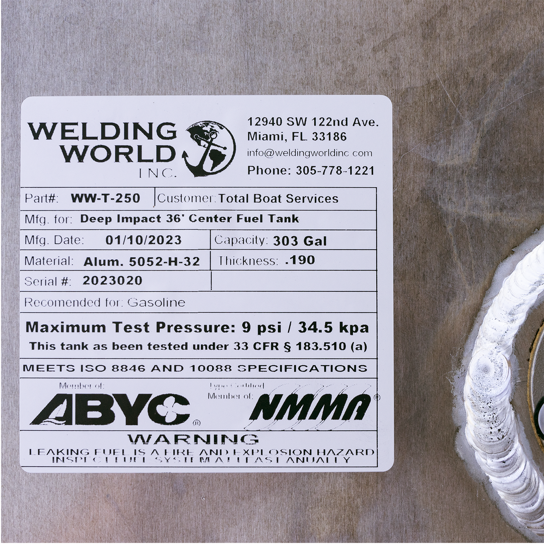 This image shows a close-up of a white label affixed to an aluminum fuel tank. The label is from Welding World Inc., located at 12940 SW 122nd Ave., Miami, FL 33186, with contact info including an email (info@weldingworldinc.com) and phone number (305-778-1221). The label specifies the part number WW-T-250 for a Deep Impact 36' Center Fuel Tank manufactured for Total Boat Services. The manufacturing date is 01/10/2023. The tank's capacity is 303 gallons, made from aluminum 5052