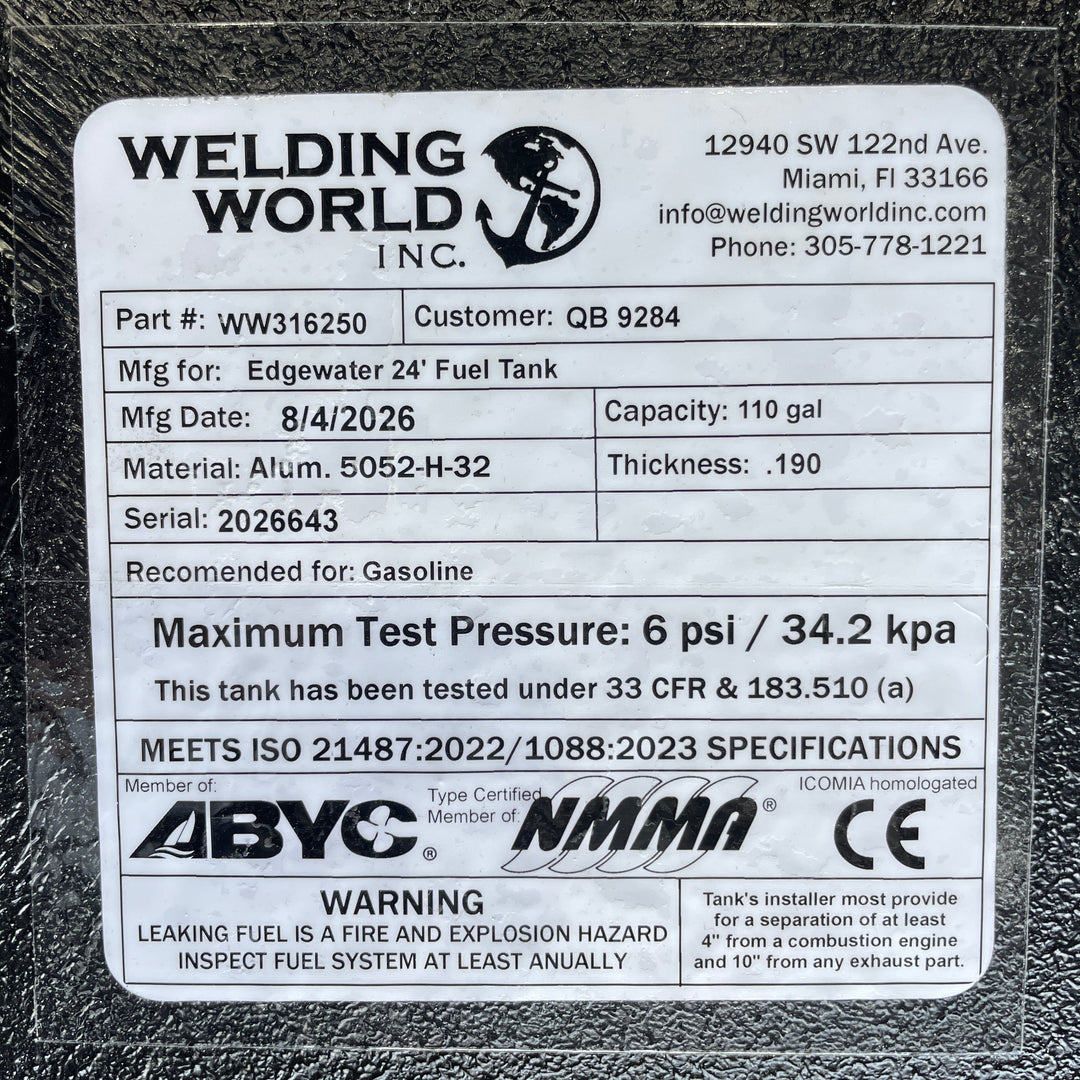 A studio macro close-up view displaying the official manufacturer certification data label on an Edgewater 24 OEM replacement marine fuel tank (110 gal) from file image_f68475.jpg, encapsulated under protective clear laminate on a black TarGard epoxy coated surface. Printed specifications verify fabrication details by Welding World Inc. in Miami, FL, including Part Number WW316250, Serial 2026643, 110-gallon capacity, .190" thickness 5052-H32 aluminum construction, 6 psi / 34.2 kPa maximum test pressure rat