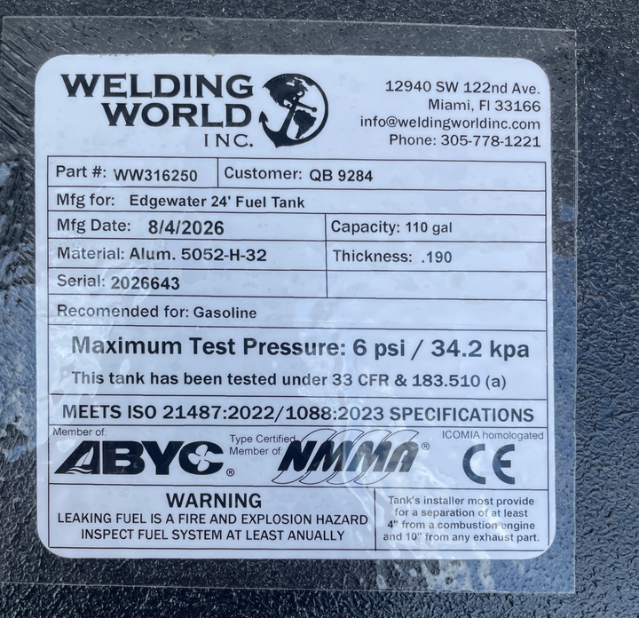 A close-up extreme macro photo displaying the official compliance specification decal label attached to the black epoxy deck of a physical Edgewater 24 OEM replacement marine fuel tank (110 gal) from file image_9c661b.jpg. Printed by manufacturer Welding World Inc. in Miami, FL, the specification plate details key manufacturing data: Part # WW316250, Customer QB 9284, Mfg Date 8/4/2026, Capacity 110 gal, Material Alum. 5052-H-32, Thickness .190, Serial 2026643, and Recommended for Gasoline. Safety ratings c