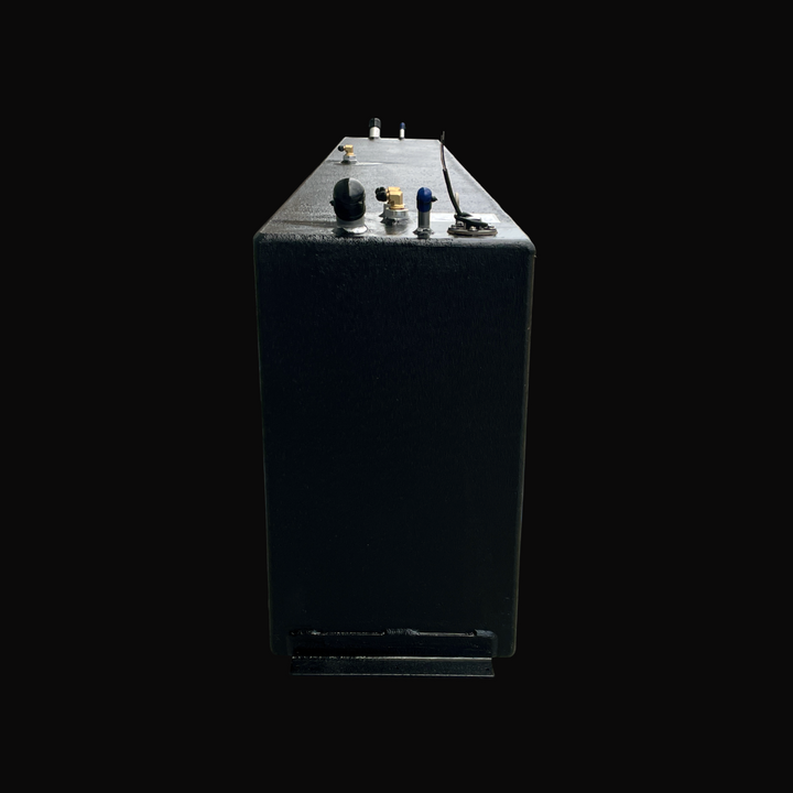 A close-up rear profile view of the Fiesta Vee Rinker 340 replacement marine fuel tank, emphasizing its tall, slim rectangular profile and a bottom-mounted mounting flange. The entire exterior is coated with a premium black TarGard epoxy finish for elite defense against corrosion in marine environments. This perspective provides a clear view of the top-deck hardware cluster, featuring a fuel fill port, a brass pickup elbow, vent fittings, and a fuel level sending unit. Precision-built by Welding World from 