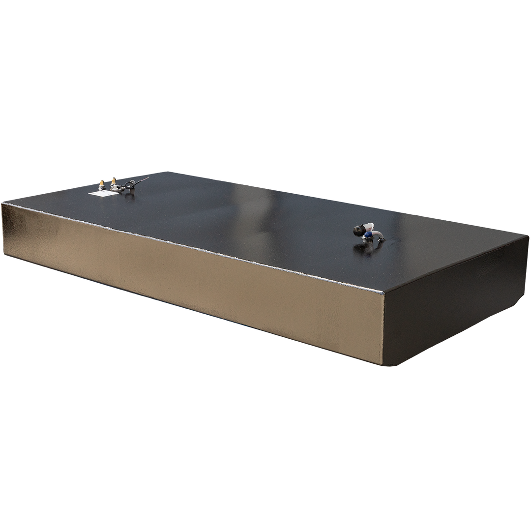 A long, rectangular, dark grey fuel tank with a reflective top surface and a textured, golden-brown side, against a black and grey checkered background. Various fittings and pipes are visible on the top surface, including golden-colored valves and a white and blue angled pipe. The front bottom corner is rounded