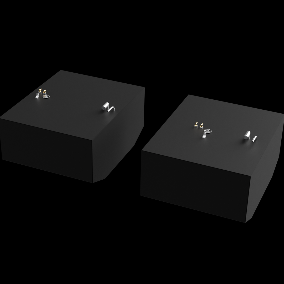 Two dark grey, rectangular fuel tanks are shown from an elevated, angled perspective against a black background with subtle white dots. Each tank has various golden and silver-colored fittings on its top surface, including pipes and valves. The tank in the foreground has a rounded bottom corner, while the tank in the background has angled bottom corners