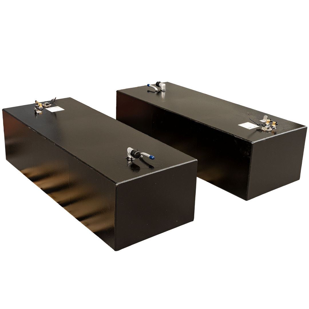 Two rectangular, black fuel tanks, each with various pipe connections and fittings on their top surfaces, are positioned on a black and grey checkered background. The tanks appear to be made of metal with a slightly glossy finish