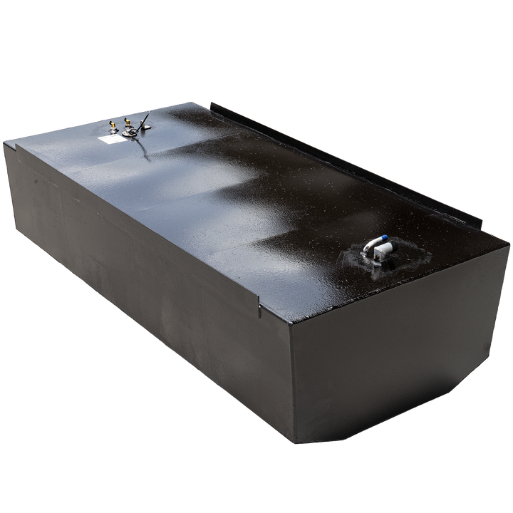 A rectangular, black fuel tank with a reflective surface is angled against a black and grey checkered background. Various metallic fittings, including two brass-colored connectors and a white and blue pipe, are visible on its top surface, along with a small white label. A raised black strip runs along the back edge of the top