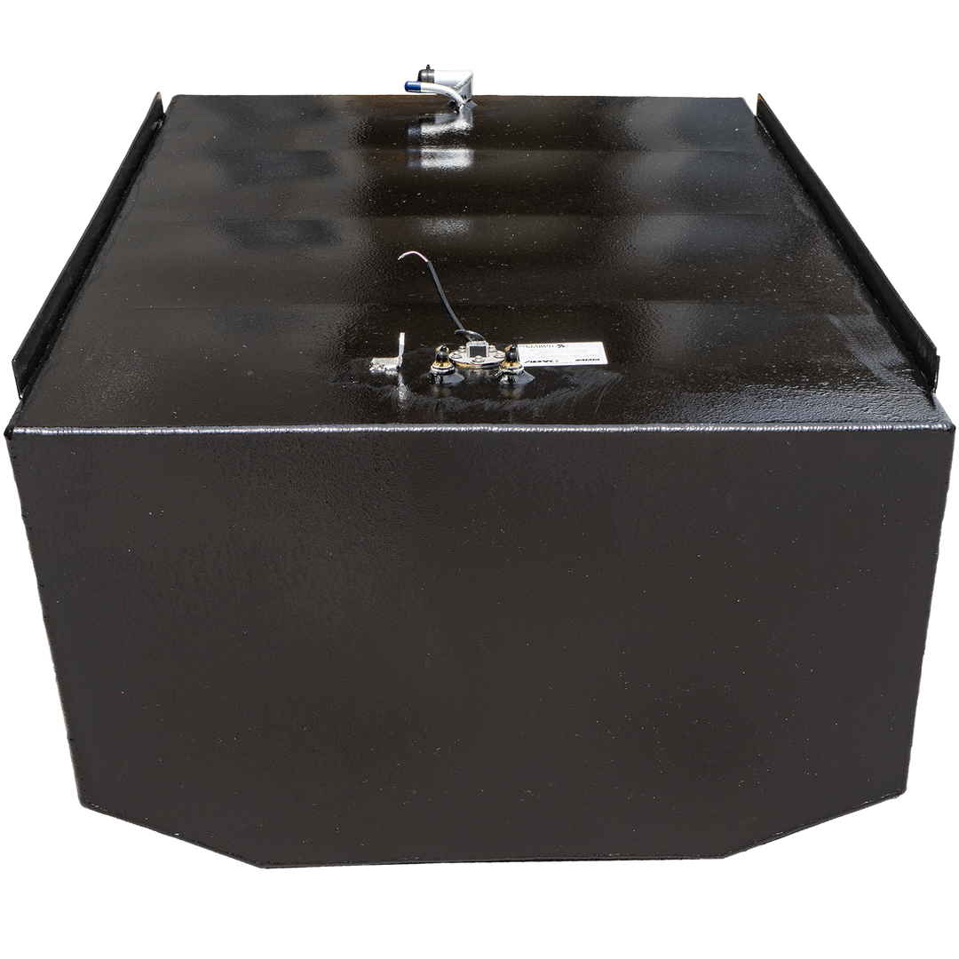 A black, rectangular fuel tank with a textured surface, shown against a black and grey checkered background. Various metallic and plastic fittings, including a white and blue tube and brass-colored connectors, are visible on its top surface, along with a small white label. A black strip runs along the top edges, creating a lip