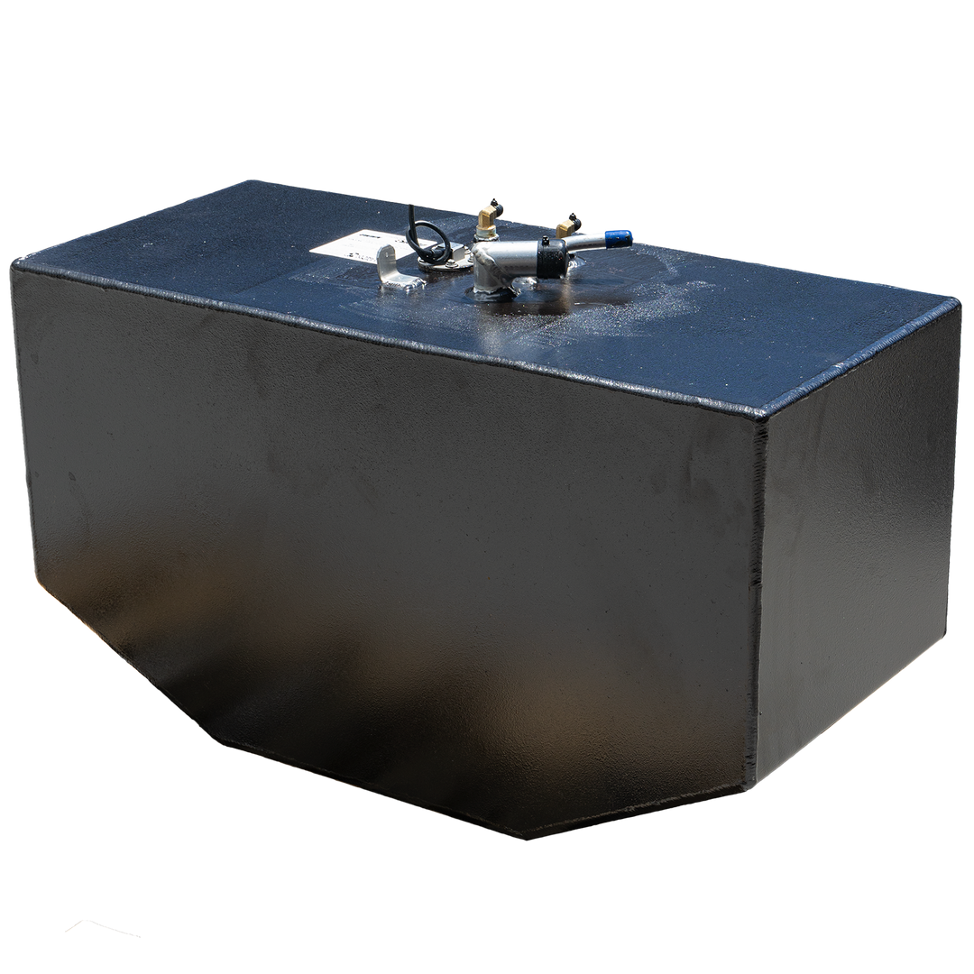 A black, rectangular fuel tank with a slightly textured finish is shown against a black and grey checkered background. Various metallic and plastic fittings are visible on its top surface, including brass-colored valves, a silver-colored component with a blue-tipped tube, and a small white label