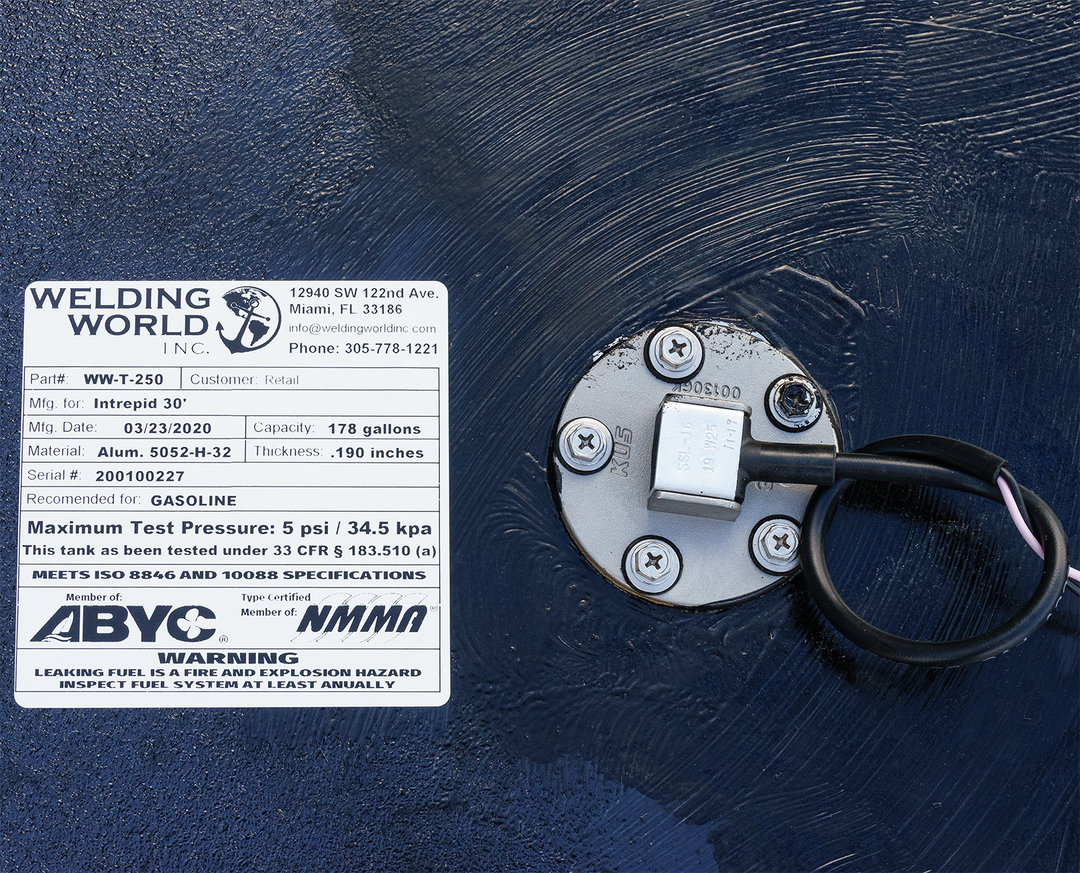 Close-up of a fuel tank combo kit for a 1991 Intrepid 30' boat, featuring two tandem belly tanks with capacities of 178 gallons and 51 gallons. The image shows a label from Welding World, Inc. detailing the tank's specifications, including model number, manufacturing date, and safety warnings regarding gasoline