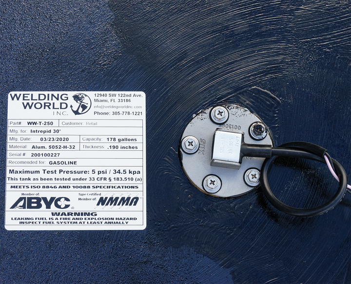 Close-up of a fuel tank combo kit for a 1991 Intrepid 30' boat, featuring two tandem belly tanks with capacities of 178 gallons and 51 gallons. The image shows a label from Welding World, Inc. detailing the tank's specifications, including model number, manufacturing date, and safety warnings regarding gasoline