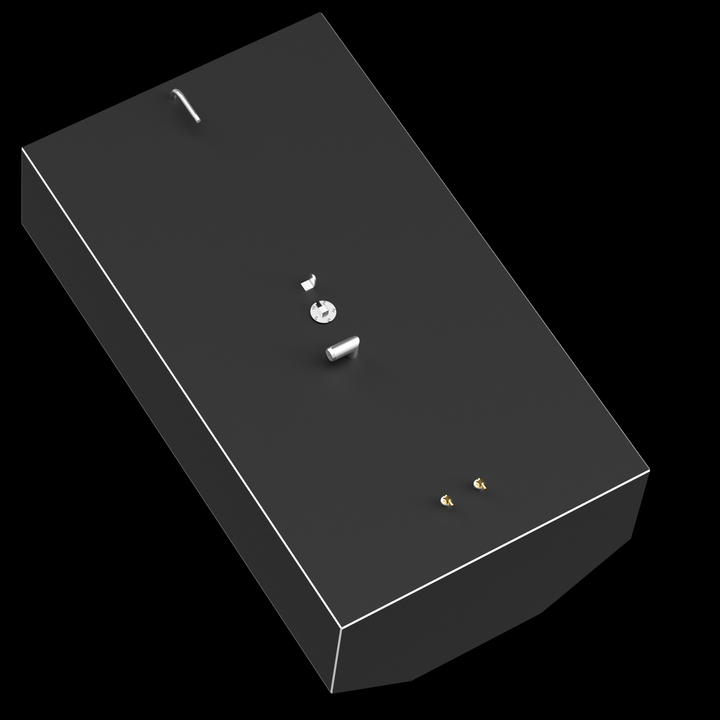 A dark gray, rectangular fuel tank with a thin white outline along its top edges, shown at an angle against a black background. Various metallic fittings, including silver-colored tubes and a circular plate, and two small brass-colored connectors, are scattered across its top surface