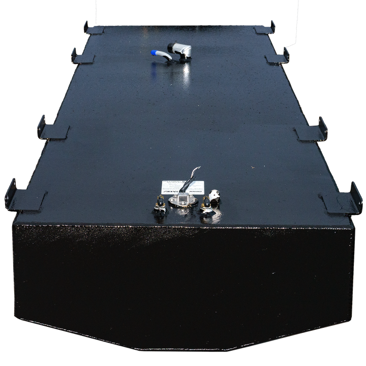 A top view of a rectangular black fuel tank, featuring a smooth surface with multiple ports, including a fuel gauge and connectors. The tank is equipped with metallic fittings and a warning label, set against a transparent checkered background