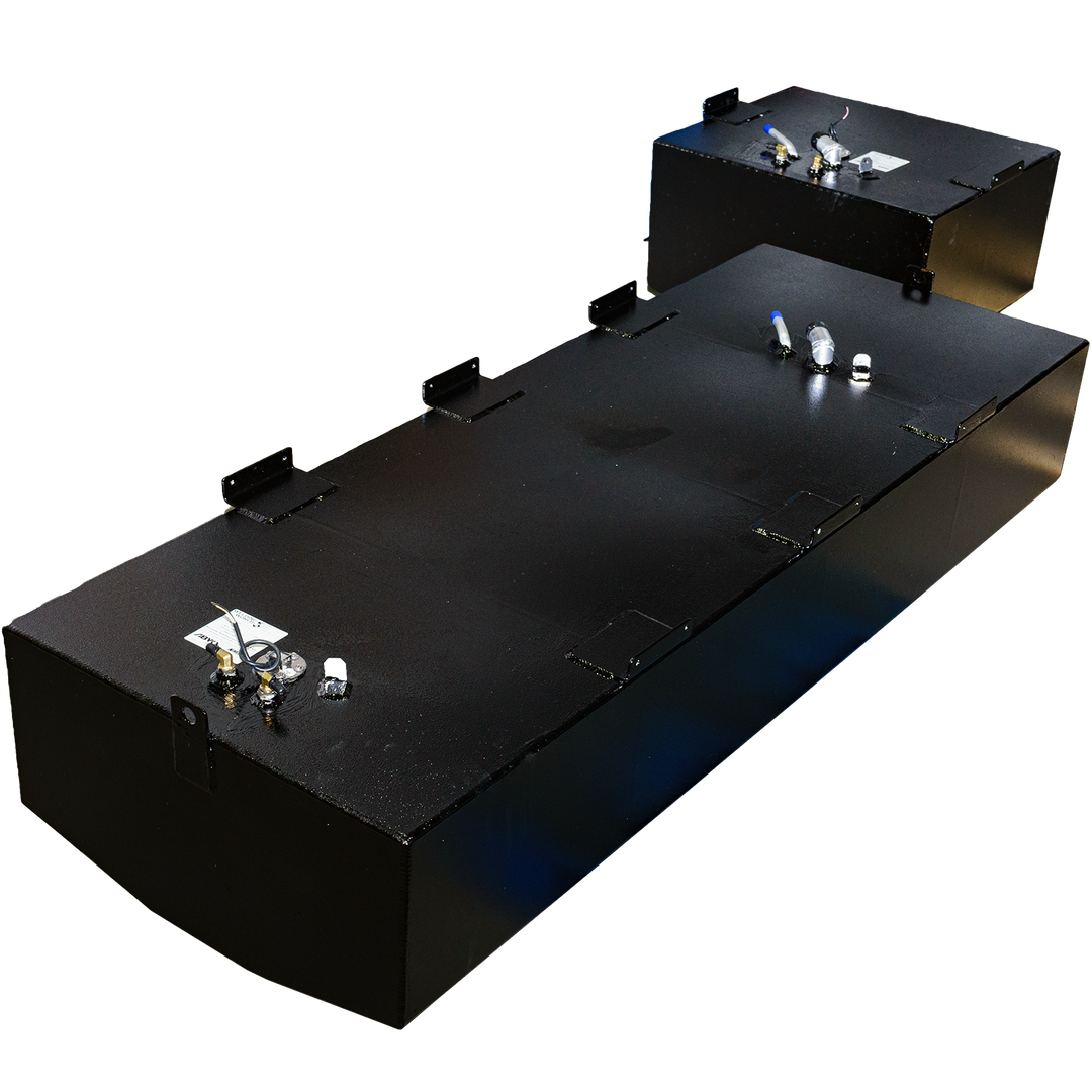An elevated view of two black rectangular fuel tanks, part of a Mako 252 - 1999 OEM Replacement Belly Fuel Tank Combo Kit, designed to hold 142 and 51 gallons respectively. The tanks have a slightly textured finish and feature various metallic fittings and connections on their top surfaces. The tanks are placed on a black and grey checkered surface, with light reflecting off their sides