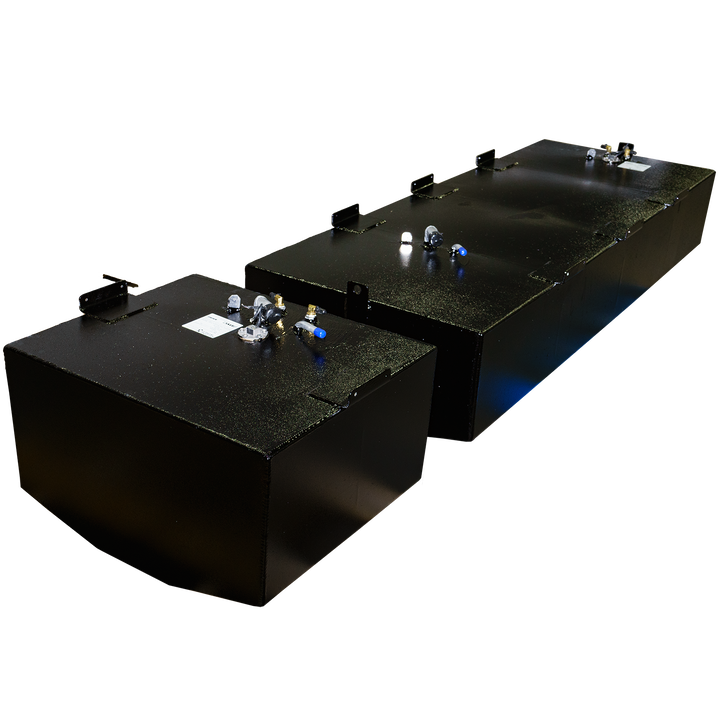 Two light gray, polygonal objects resembling industrial tanks or containers are set against a solid black background. The larger, rectangular object is in the foreground, featuring several small protrusions and a circular element on its top surface. Behind it and slightly to the left, a smaller, cubic object is visible, also with some features on its top.