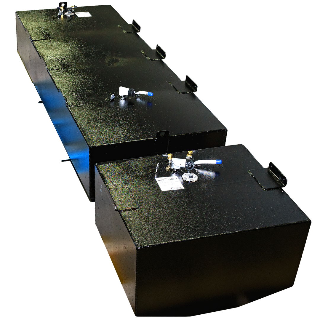 Two light gray, polygonal objects resembling industrial tanks or containers are set against a solid black background. The larger, rectangular object is in the foreground, featuring several small protrusions and a circular element on its top surface. Behind it and slightly to the left, a smaller, cubic object is visible, also with some features on its top