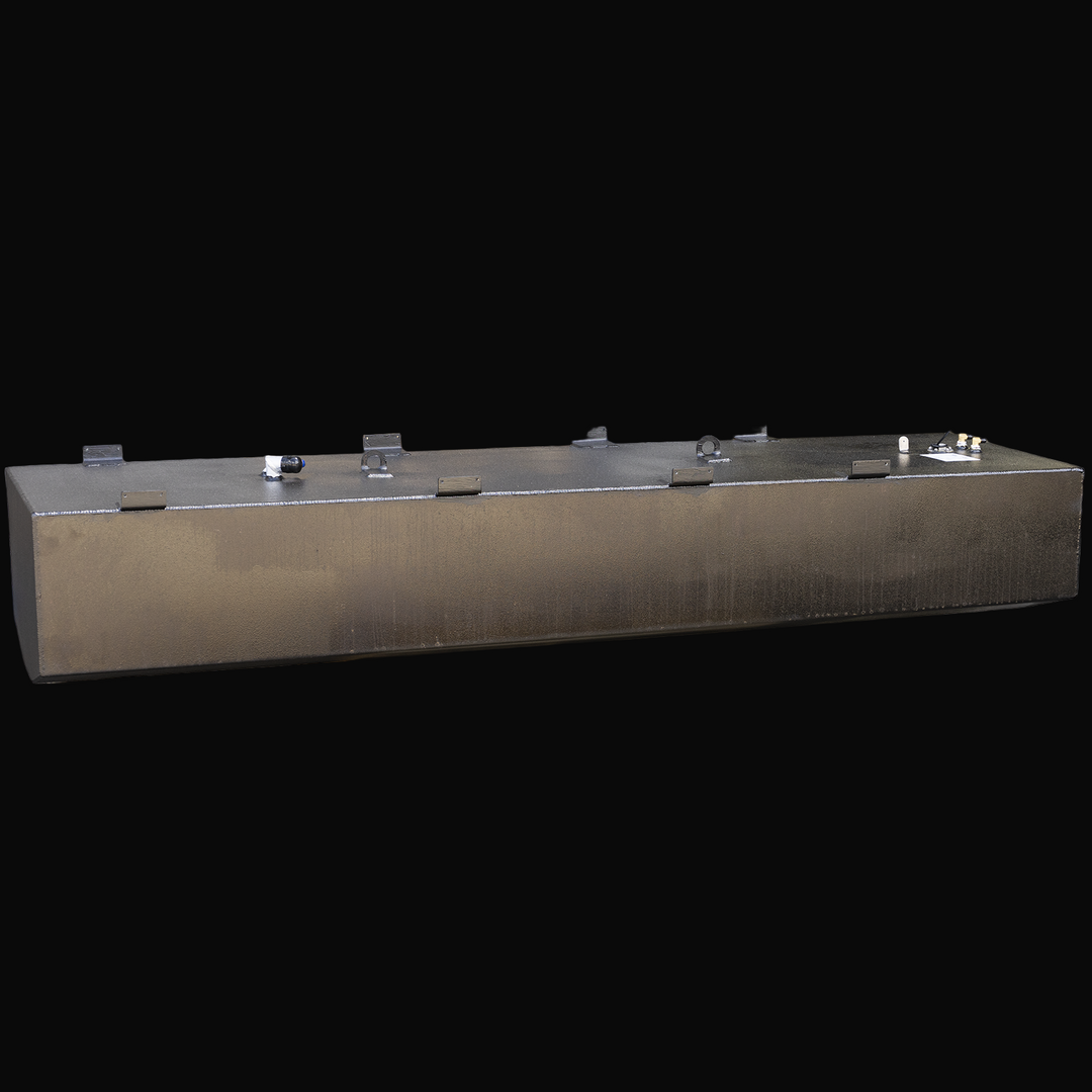 Long rectangular black metal fuel tank with welded mounting brackets along the top edges, several fittings and a fuel sending unit on top, photographed at an angle showing the front and top surfaces with a textured finish