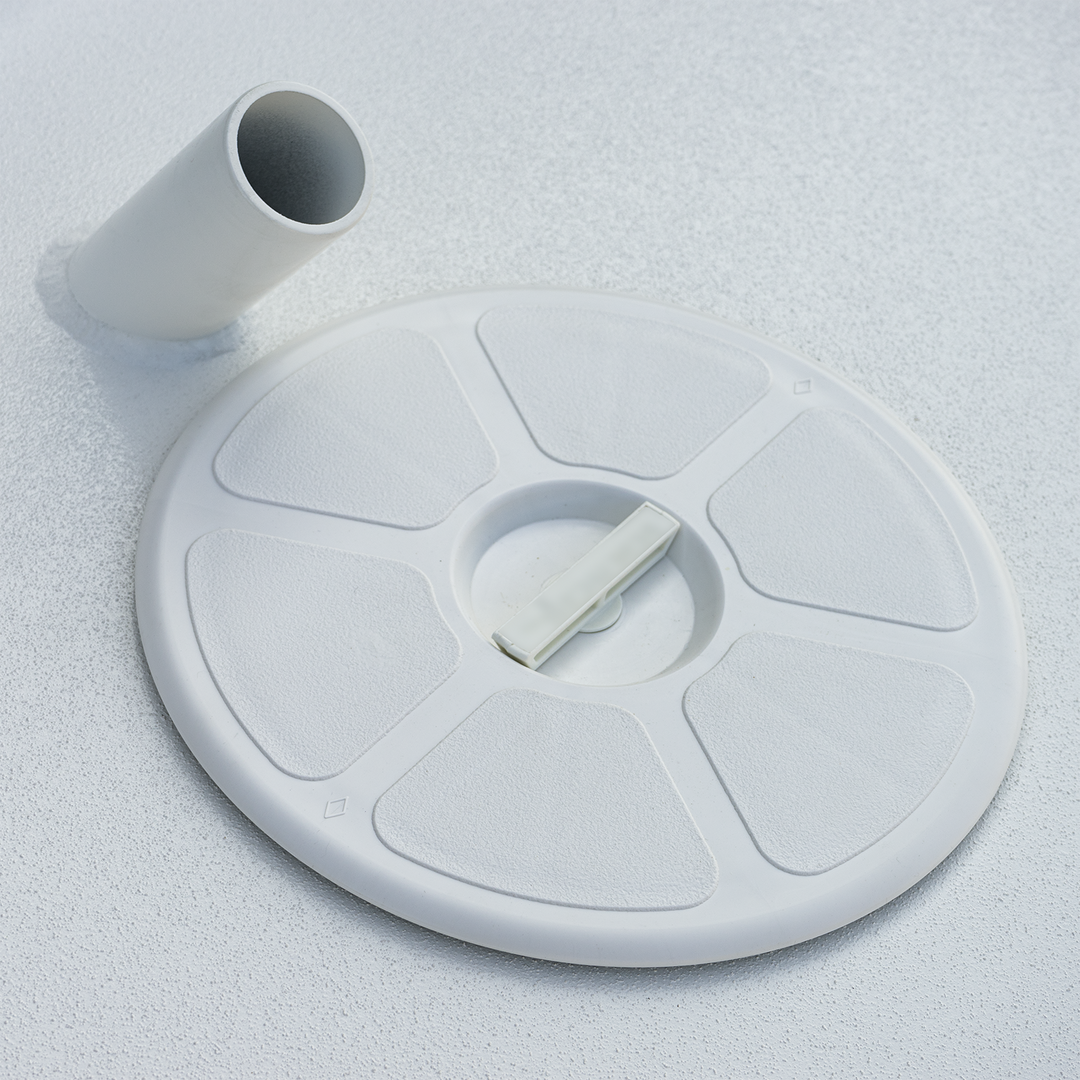 A white circular high flotation bracket with a central locking latch, and a separate cylindrical pipe component, both placed on a textured white surface. The bracket appears to be part of a marine or boat assembly system