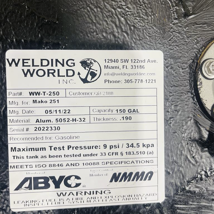 A white product label from "WELDING WORLD INC." is affixed to a black, textured surface. The label provides detailed specifications for a fuel tank: Part# WW-T-250, Mfg. for Mako 251, Mfg. Date 05/11/22, Capacity 150 GAL, Material Alum. 5052-H-32, Thickness .190, and Serial # 2022330. It is recommended for Gasoline, has a maximum test pressure of 9 psi / 34.5 kpa, and meets ISO 8846 and 10088 specifications. The label also includes contact information for Welding World Inc. and a warning about leaking fuel