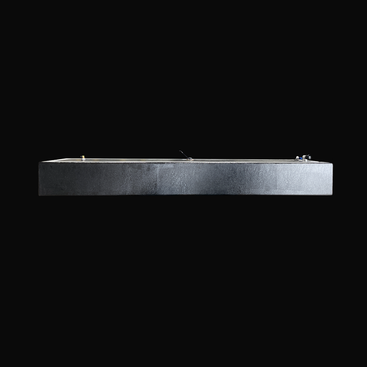 An eye-level studio side profile view of a physical, finished black encapsulated Proline 21 OEM replacement marine fuel tank (84 gal 1994) from file image_152501.png, isolated against a black background. Precision-fabricated from heavy-gauge marine-grade 5052-H32 aluminum, the long low-profile body is fully encapsulated in a protective, textured black TarGard epoxy coating to resist severe saltwater pitting and bilge corrosion. Visible top deck hardware includes a forward-mounted 90-degree aluminum fuel fil