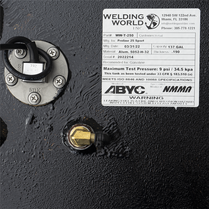  A close-up view of a black, textured surface, likely part of a fuel tank. In the upper left, there's a circular metal fitting secured by four screws, with a black hose connected to it. To the right, a white label from "WELDING WORLD INC." provides specifications for a "Proline 25 Sport" fuel tank, including "Part# WW-T-250", "Capacity 137 GAL", "Material Alum. 5052-H-32", and "Serial# 2022214"