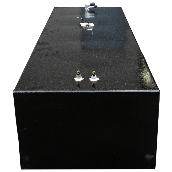 A top-down view of a rectangular, black fuel tank with a speckled, granular surface, set against a black and grey checkered background. The tank features various fittings, including two brass-colored valves with white bases, and a silver pipe with blue and black accents