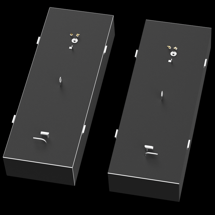 Two identical, dark grey, elongated rectangular fuel tanks are shown from an overhead, angled perspective. Each tank features golden-colored fittings, a circular silver cap, a straight pipe, an L-shaped pipe, and a D-ring on its top surface. White brackets are visible along the long sides, and a thin white line outlines the top edge of each tank. The tanks are set against a solid black background