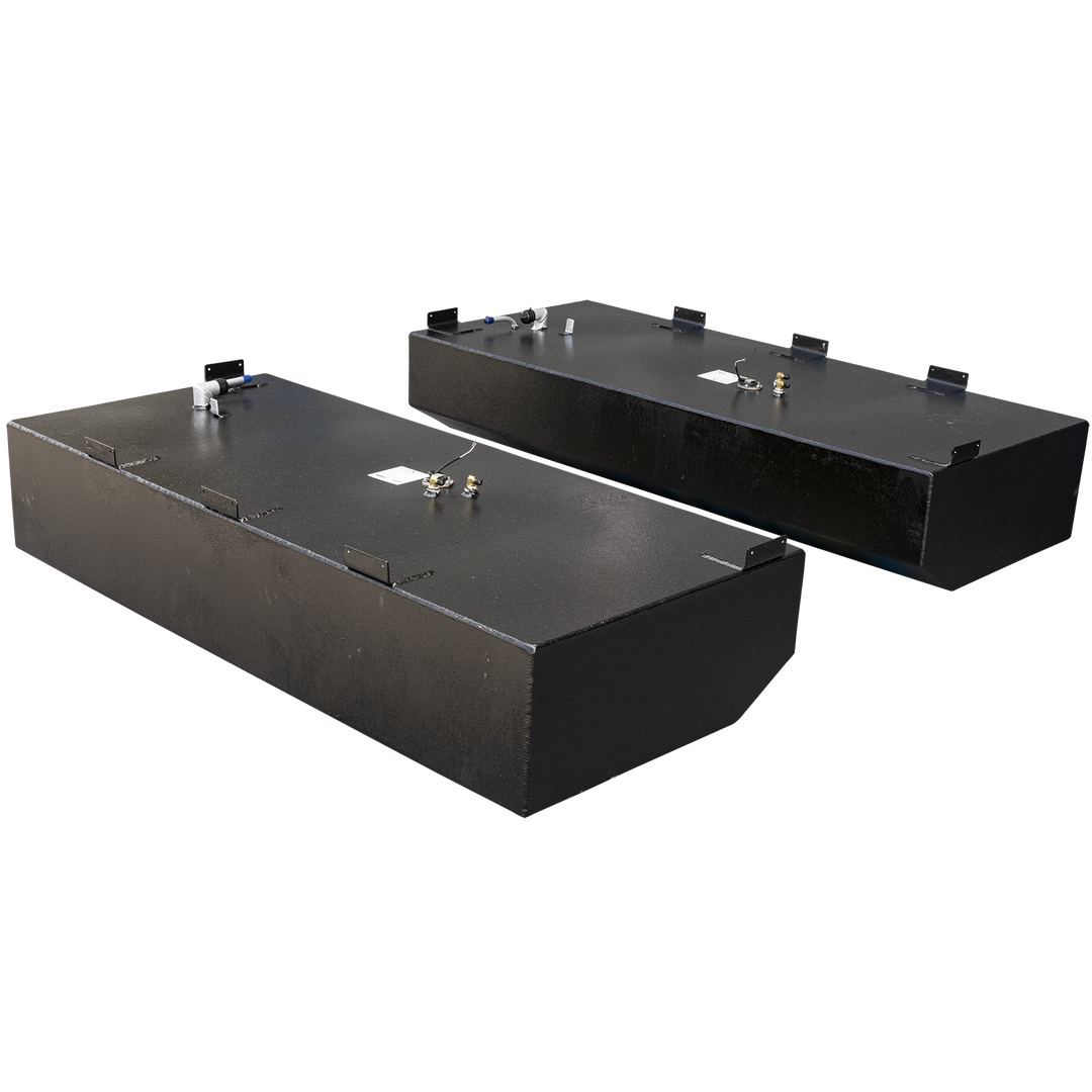 Two black, rectangular Pursuit 2879 WA 2001 OEM Replacement Saddle Fuel Tanks are shown, each with slightly different features. The tank in the foreground has a rounded front edge, while the one in the background is fully rectangular. Both tanks have several fittings and connection points on their top surfaces, and metal brackets are attached to their top edges