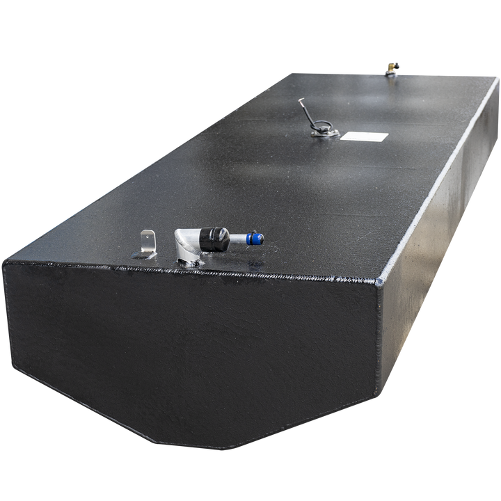 A long, rectangular, black boat fuel tank with a textured surface. Various metal fittings are visible on its top, including a hose connection with a blue cap, a small U-shaped bracket, a circular sensor with wires and a white label, and a small golden post. The bottom of the tank has a curved edge